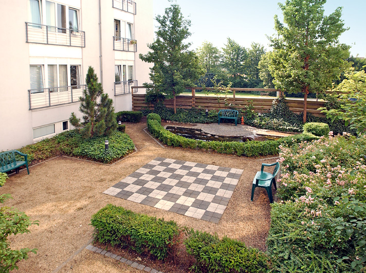 Garten im Gemeinschaftsbereich mit Sitzmöglichkeiten und einem großen Schachbrett auf dem Boden